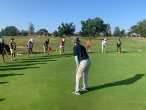Golf instructor teaching class on putting green